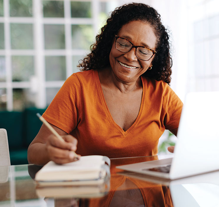 A woman writing her planned giving. Links to Gifts by Will A woman writing her planned giving. Links to Gifts by Will