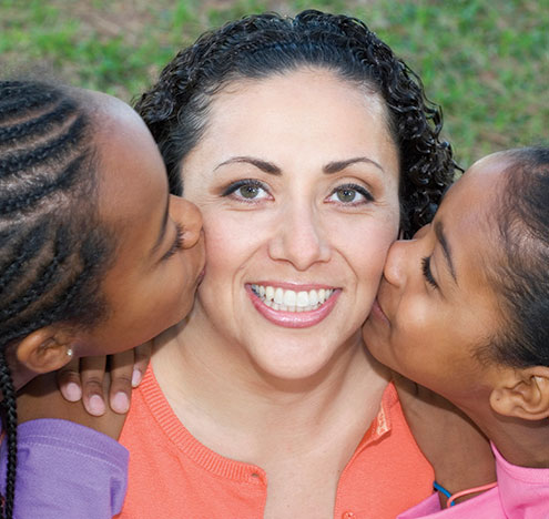 Two girls kissing the cheek of a woman. Links to Gifts of Appreciated Securities